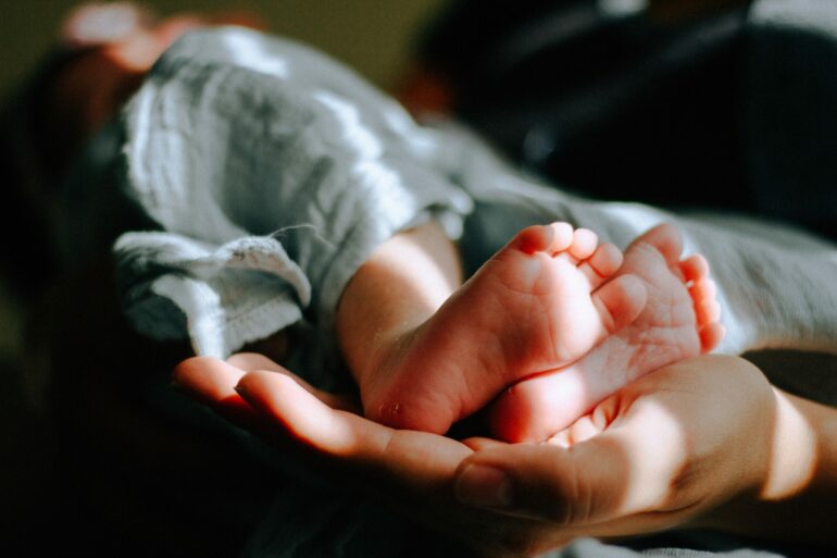 En förälder som håller i en bebis fötter